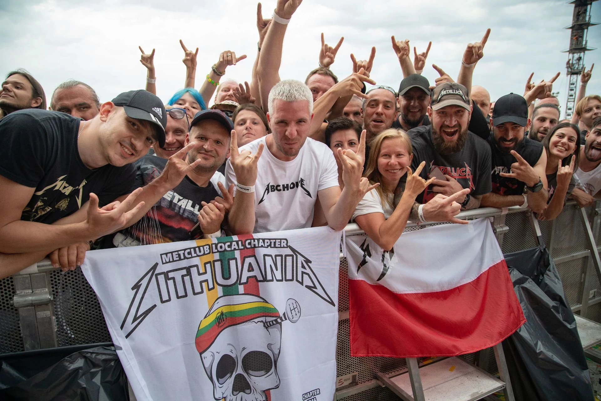 Metallica fanų bendruomenė prie atitvaro su balta LITHUANIA klubo vėliava